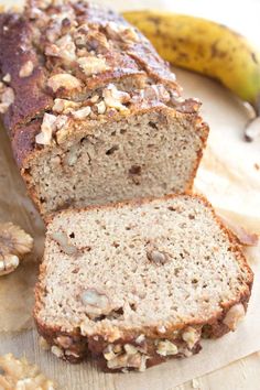 a loaf of banana nut bread sitting on top of a cutting board next to a ripe banana