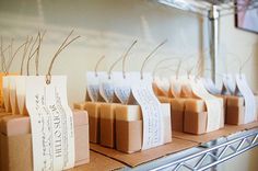 several soap bars are lined up on a shelf with tags attached to them and some candles in the background