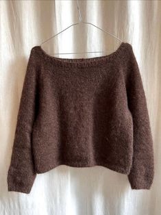 a brown sweater hanging on a white curtain