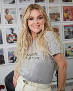 a woman with long blonde hair standing in front of a wall full of comic books