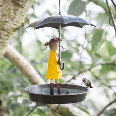 a bird feeder with a figurine holding an umbrella