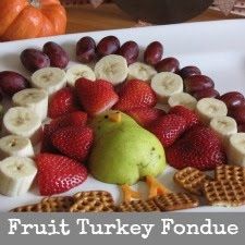 a turkey made out of fruit and crackers on a plate with a turkey in the background