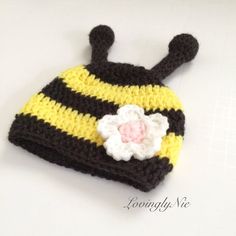 a crocheted hat with a flower on the front and black, yellow, and white stripes