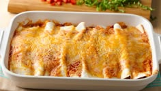 a casserole dish with meat and cheese in it on a table next to tomatoes