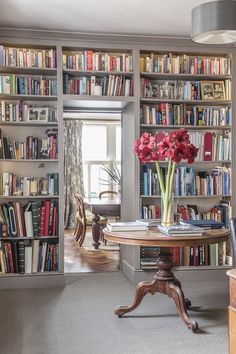 a room filled with lots of books and a table in front of a book shelf