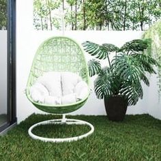 a green chair sitting in the grass next to a potted plant