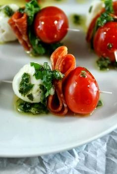 small appetizers with tomatoes and mozzarella are on a white platter