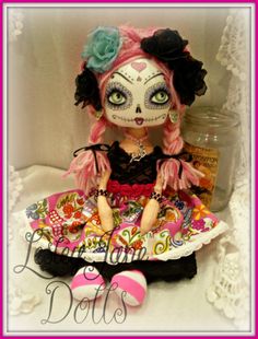 a doll sitting on top of a white table next to a pink and black heart