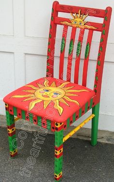 a red and green painted chair sitting in front of a garage door with the sun on it