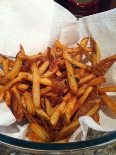 french fries are piled up in a glass bowl