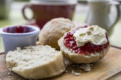 some type of bread with cream and jam on it next to a cup of coffee