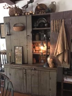 an old wooden cabinet with many items on top and some lights in the corner next to it