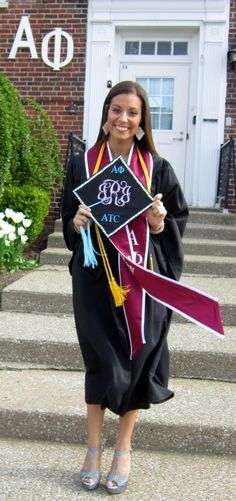 a woman in graduation gown holding a sign