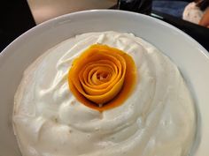 a white plate topped with whipped cream and an orange flower