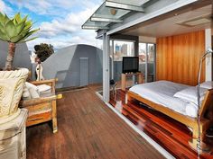 a bed sitting on top of a wooden floor next to a tv mounted to a wall