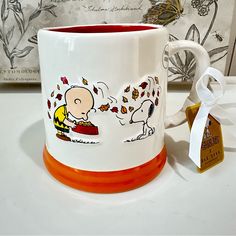 a coffee mug with a charlie brown sticker on it next to a white ribbon