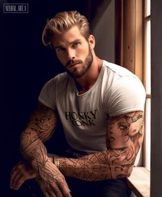 a man with tattoos sitting on a window sill