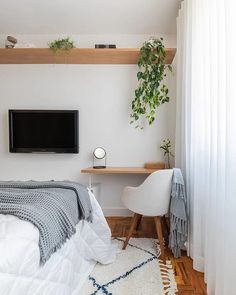 a bedroom with a bed, desk and television on the wall in it's corner