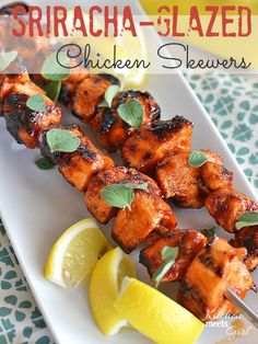 chicken skewers with lemon wedges and mint garnish on a white plate