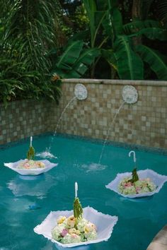 three paper plates filled with food floating in a pool