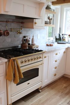 a stove top oven sitting inside of a kitchen next to white cabinets and counter tops