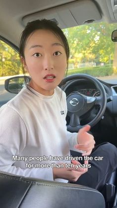 a woman sitting in the driver's seat of a car talking to someone else