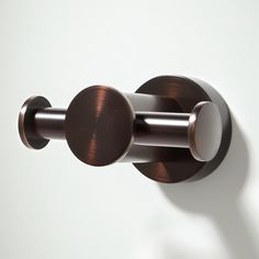 a close up of a metal object on a white wall with brown and silver accents