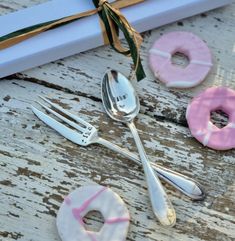 pink and white doughnuts with forks tied to them next to a gift box