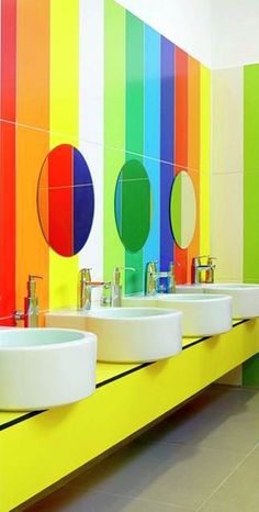 a bathroom with three sinks and rainbow colored walls