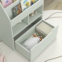 an open book shelf on the floor with books and other items in it, next to a toy car