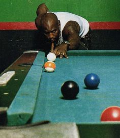 a man leaning down to pick up balls on a pool table