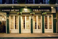 the front of a two sisters restaurant at night with lights on and windows lit up