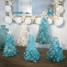 three blue and white christmas trees sitting on top of a wooden table next to a mirror