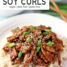 a white plate topped with rice covered in meat and green onions next to chopsticks