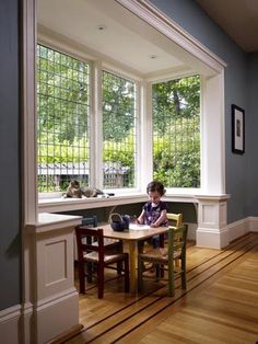 a child sitting at a table in front of two windows