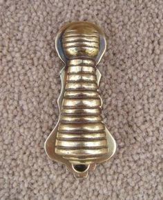 a gold colored metal object sitting on top of a carpeted floor next to a wall