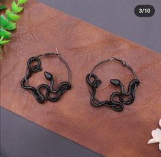 two pairs of black beaded hoop earrings sitting on top of a wooden table next to flowers