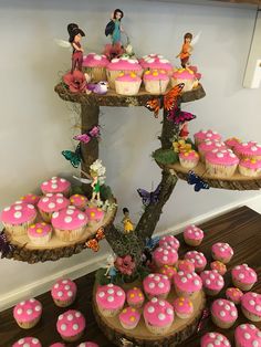 there are cupcakes and muffins on this tree stump with pink frosting