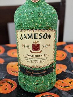 a bottle of jameson sitting on top of a table covered in green glitter and pumpkins