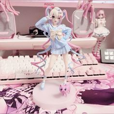 an anime figurine sitting on top of a desk next to a computer keyboard