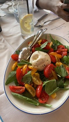 a white plate topped with lots of veggies next to a glass of water