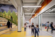 people are walking around in an open area with yellow flooring and walls painted with colorful images