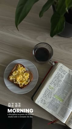 an open book on a table next to a plate with eggs and toast in it