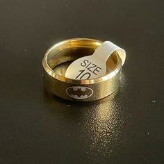 a gold ring with a batman symbol on it and the word size written in white