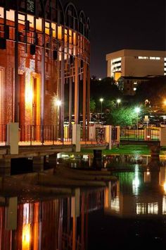 the city is lit up at night and reflecting in the water