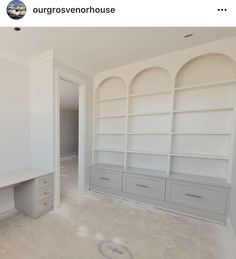 an empty room with white shelves and drawers