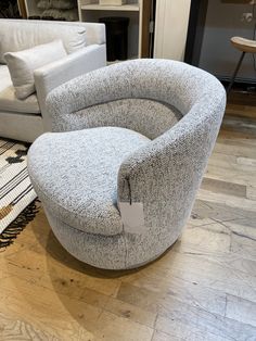 a chair with a tag on it sitting in front of a white couch and other furniture