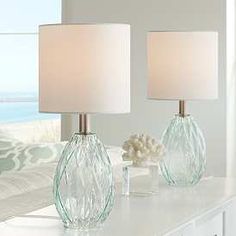 two glass lamps sitting on top of a white table