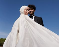 a man and woman in tuxedos are posing for a photo with the sky behind them