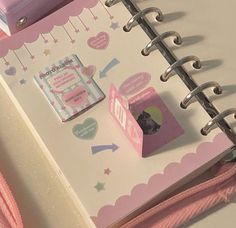 a pink and white binder on top of a notebook with a cat in it